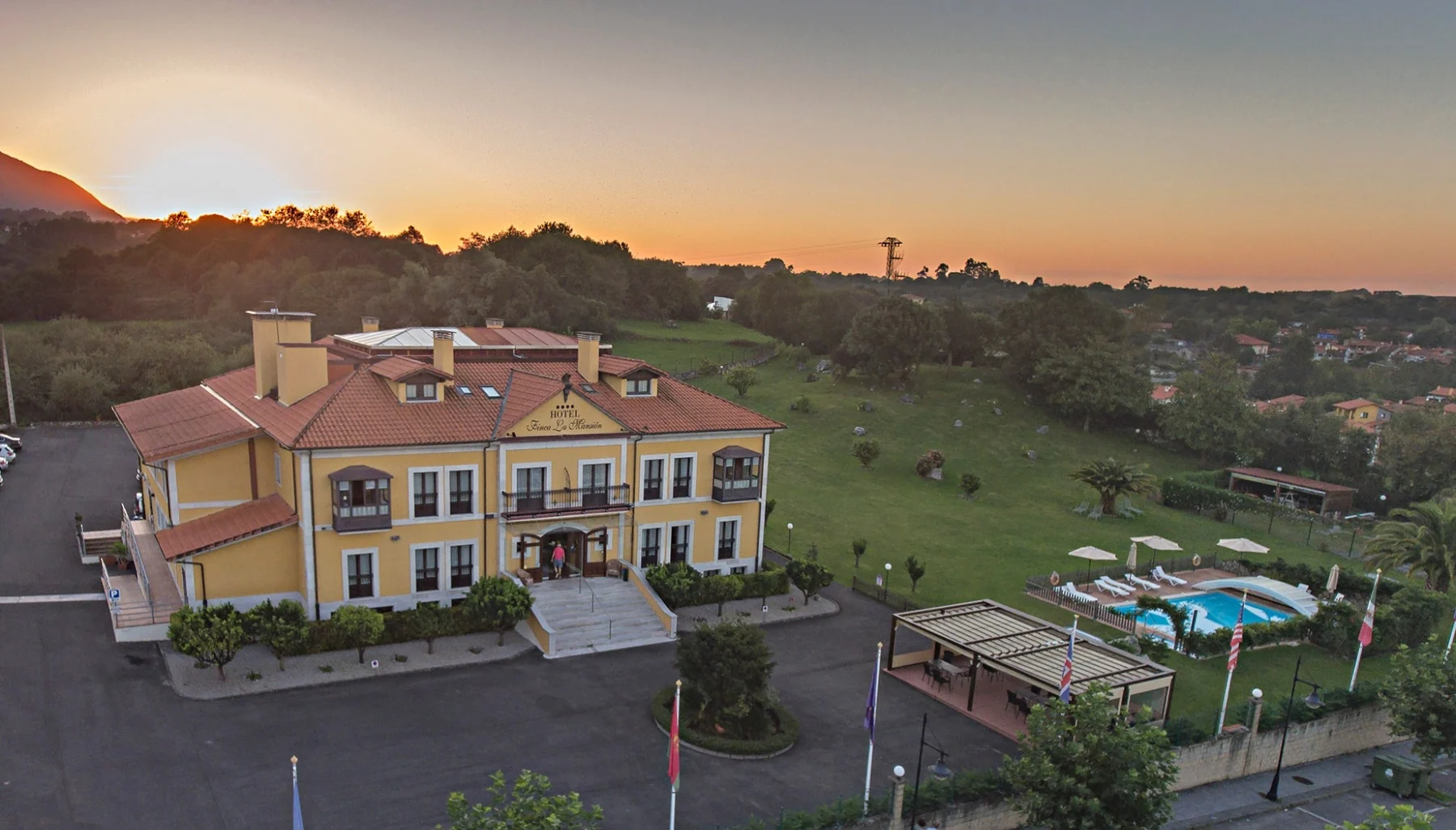Aerial view of the hotel, garden and pool at sunset